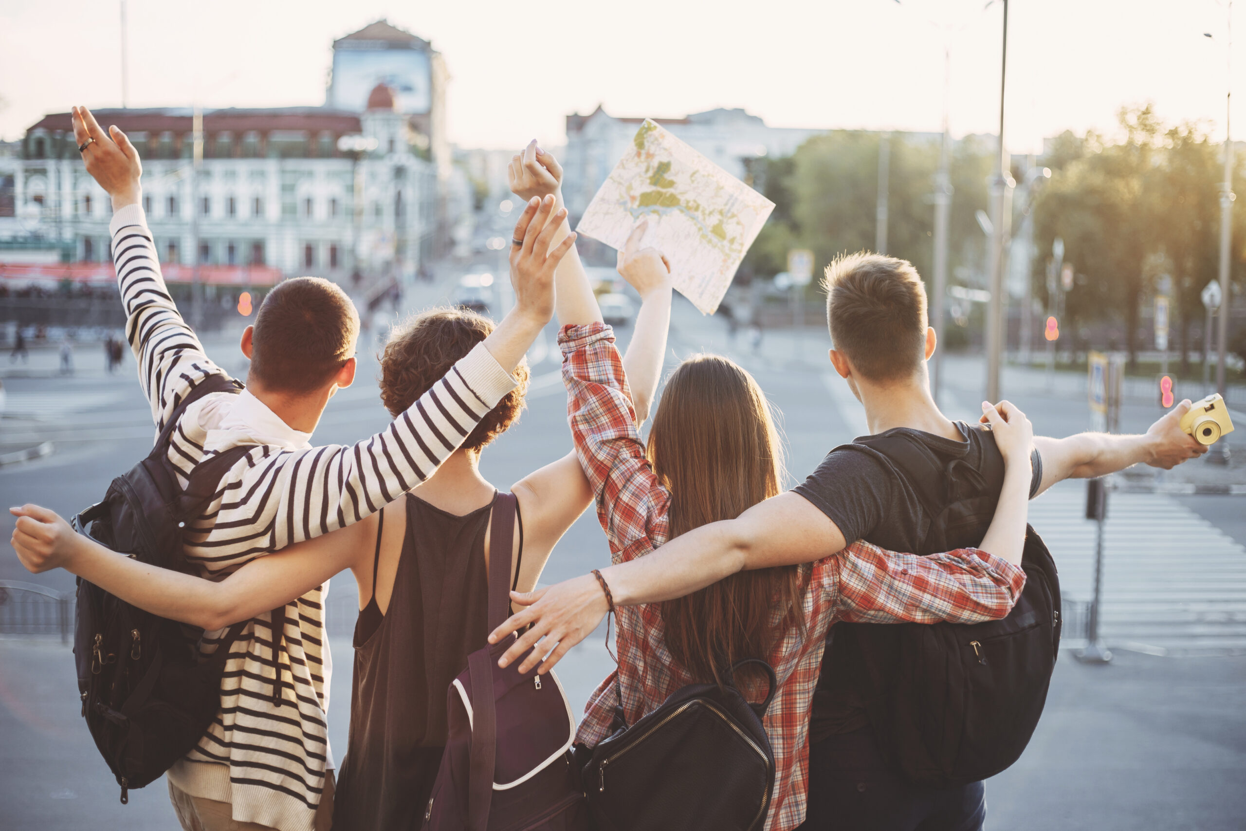 Friends,Traveling,Together.,Cheerful,Students,With,Backpacks,Rising,Hands,At